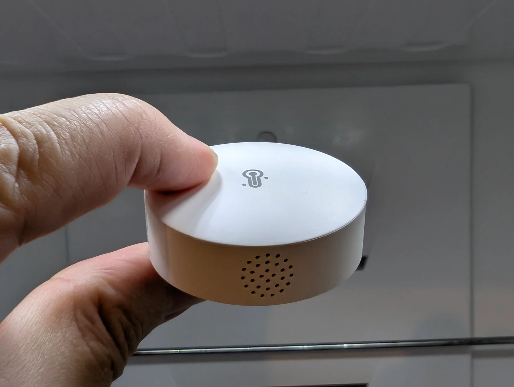SONOFF SNZB-02P temperature and humidity sensor held in front of an appliance